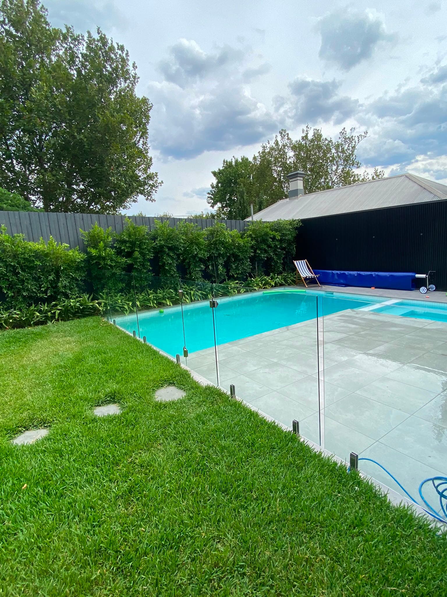 Completed Gabbe project: modern pool with paved deck, glass fencing and gardens